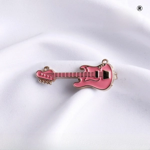 Macro detail of a pink electric guitar brooch pin with gold-plated metal accents