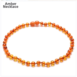 Macro detail of fire amber necklace beads with secure screw clasp on white background