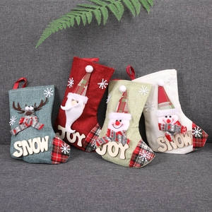 Détail de quatre chaussettes de Noël en lin avec figurines 3D Père Noël et bonhomme