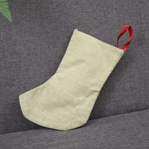 Gros plan de la chaussette de Noël en lin beige avec boucle rouge sur un canapé gris