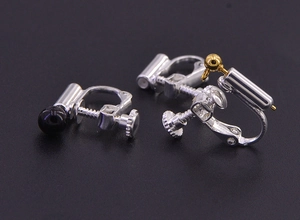 Macro detail of silver screw-back earring converter with black bead and gold hook
