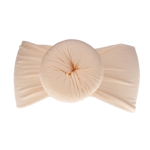 Dettaglio fascia per neonati in nylon beige morbido con decorazione a palla pieghettata