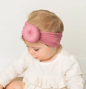 Dettaglio della fascia rosa per neonati con nodo donut in morbido nylon lavorato