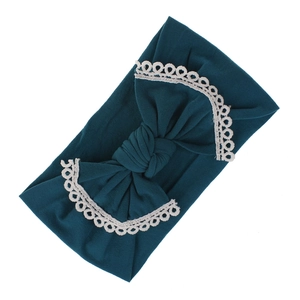 Detail of soft ribbed nylon baby headband with lace-edged bow in dark green