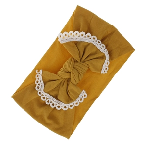 Detail view of mustard yellow baby headband with soft nylon bow and white lace trim