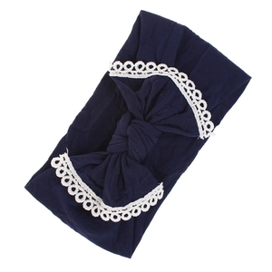 Detailed view of dark blue baby headband with large bow and delicate white lace trim