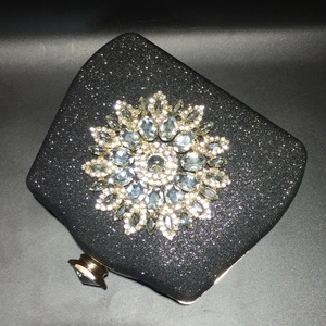 Detail of a black glitter evening bag featuring a radiant crystal sunflower centerpiece
