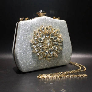 Silver glitter evening bag featuring a large crystal floral emblem with a gold metal clasp