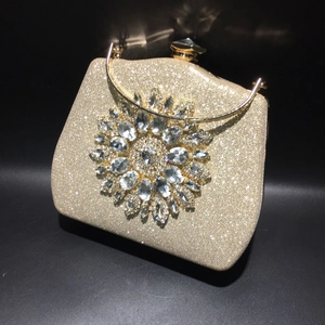 Detailed view of luxury gold clutch bag with sunflower rhinestone ornament and handle