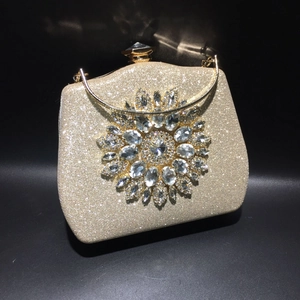 Detailed close-up of golden evening clutch featuring crystal sunflower ornament and glitter finish