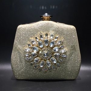 Close-up of golden evening clutch featuring a sparkling rhinestone sunflower ornament
