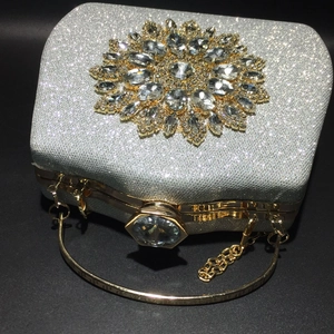 Close-up of silver glitter evening bag with large crystal sunflower and gold hardware