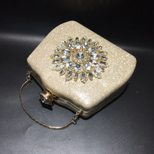 Macro detail of gold evening clutch with sparkling sunflower rhinestones and metal handle