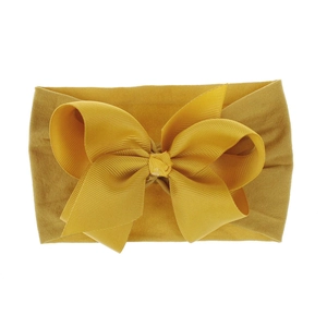 Nahaufnahme eines weichen, senfgelben, elastischen Nylon-Bogenstirnbands für Babys