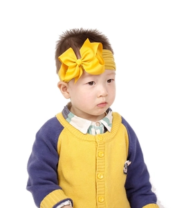 Nahaufnahme eines Babys mit einem großen gelben Schleifenband aus weichem Nylon-Zubehör