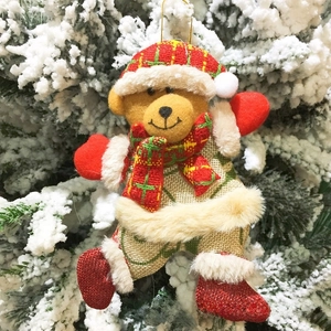 Detail eines Weihnachts-Teddybären mit festlichem Karostoff an einem Schneebaum