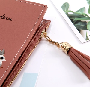 Detail of red-brown leather wallet with gold chain tassel and bird embroidery