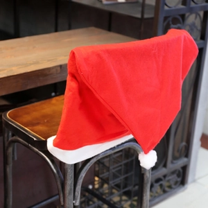 Red Christmas hat chair covers with white plush pompom in a rustic cafe setting
