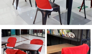 Detail of red Santa hat chair covers with white plush trim and pom-poms on dining chairs