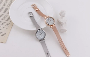 Detail of marble dial ladies watches with rose gold and silver mesh straps on white decor