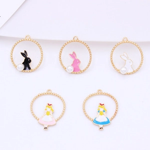 Detail of round gold charms featuring Alice and rabbit themes with faux pearl accents