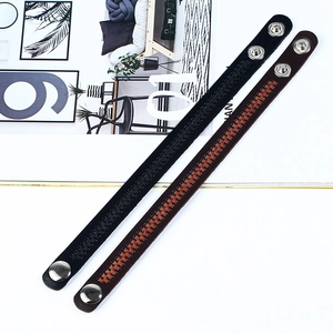 Detail view of black and brown faux leather bracelets with woven texture and snap buttons