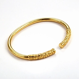 Detailed view of gold steel cuff bracelet featuring intricate relief texture ends