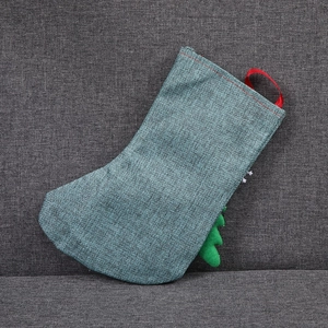Close-up of a teal linen Christmas stocking with a red loop and green felt tree detail