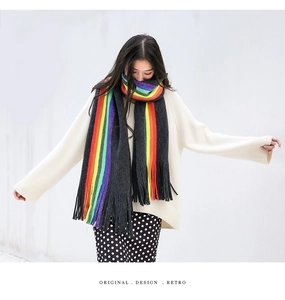 Close-up of a rainbow striped knitted scarf with long tassels and deep gray base