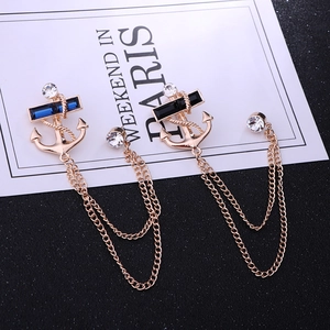 Detail of golden anchor brooches with blue and black gems and double tassel chains