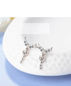 Detail of silver angel wing key earrings with sparkling heart-shaped zircon drop