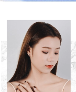 Detailed view of silver angel wing earrings with delicate hanging tassel chains on model