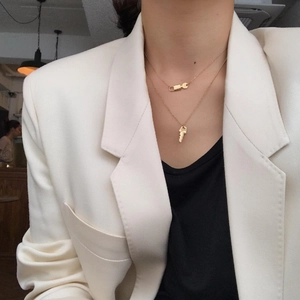 Close-up of layered gold 925 silver necklaces with lock and key pendants worn on a model