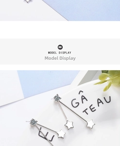 Detail view of star drop earrings and zircon studs on a decorative white porcelain dish