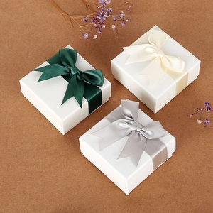 Elegant white square jewelry gift boxes featuring silk bows and decorative dried flowers