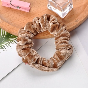 Detail of brown velvet scrunchie on wooden tray with cozy lifestyle accessories