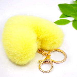 Detail view of a fluffy yellow heart-shaped plush keychain with gold-tone hardware