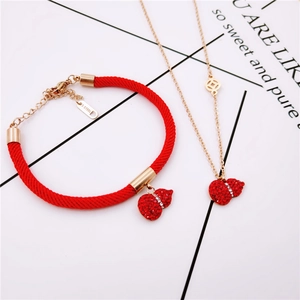 Dettaglio del bracciale rosso e della collana in oro rosa con ciondolo a zucca
