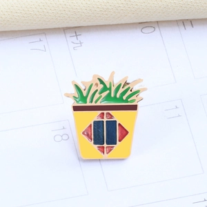 Close-up of a potted plant enamel brooch with yellow pot and green leaves on a calendar
