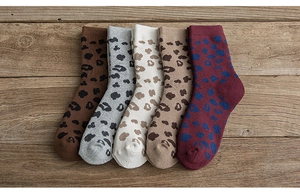 Detailed knit texture of five pairs of warm leopard print crew socks on wooden surface
