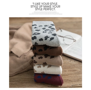 Detail of five colors winter warm knitted socks with heart leopard print on wooden table