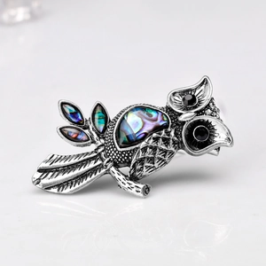 Vintage owl brooch featuring iridescent abalone shell wings and black gem accents