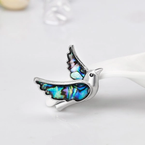Macro detail of bird brooch featuring natural abalone shell wings and silver frame