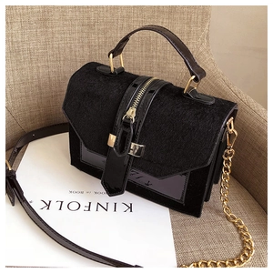 Detail of black crossbody bag with gold chain strap and mixed texture materials