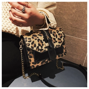 Detail of leopard print crossbody bag with gold chain and polished black trim