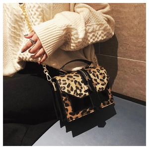 Close-up of leopard print crossbody bag with gold chain strap on knit sweater