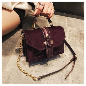 Macro view of burgundy glitter fabric and patent leather detail on luxury chain bag