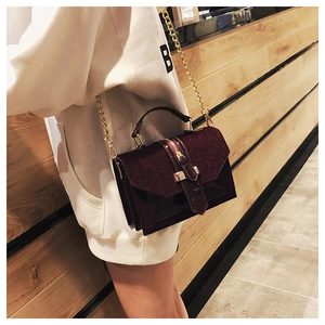 Detail of burgundy crossbody bag with sequins and shiny leather finish on model