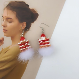 Close-up of strawberry cake earrings with red plaid bow and soft white plush pom-pom