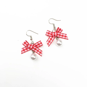 Detail of red checkered bow earrings with white pearl pendant and silver hooks